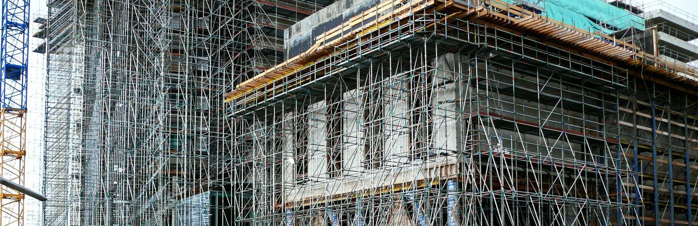 Un chantier de bâtiment sous échafaudage, avec une grue.