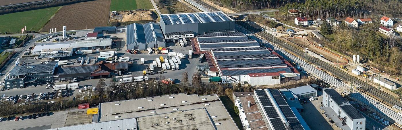 Vue aérienne d'une zone logistique : les hangars, la cour et les semi-remorques à quai.